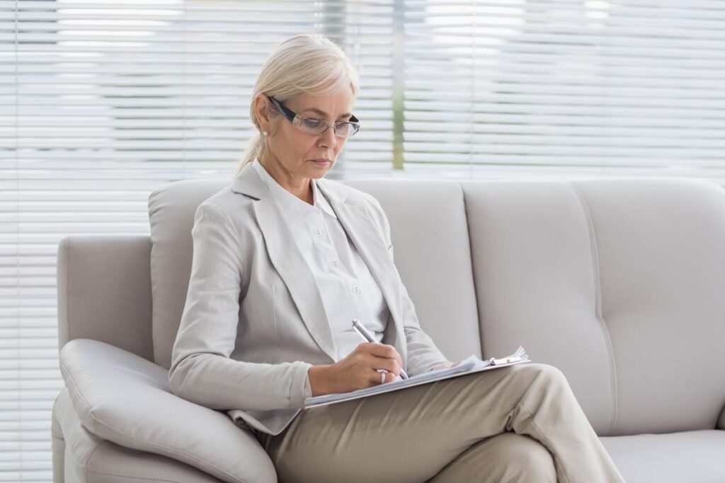 a person sits on a couch writing tips for writing therapy notes