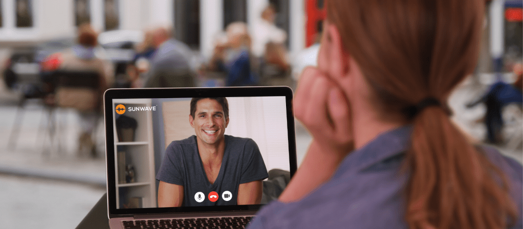 young man on laptop screen smiling while talking to medical professional via telehealth conferencing