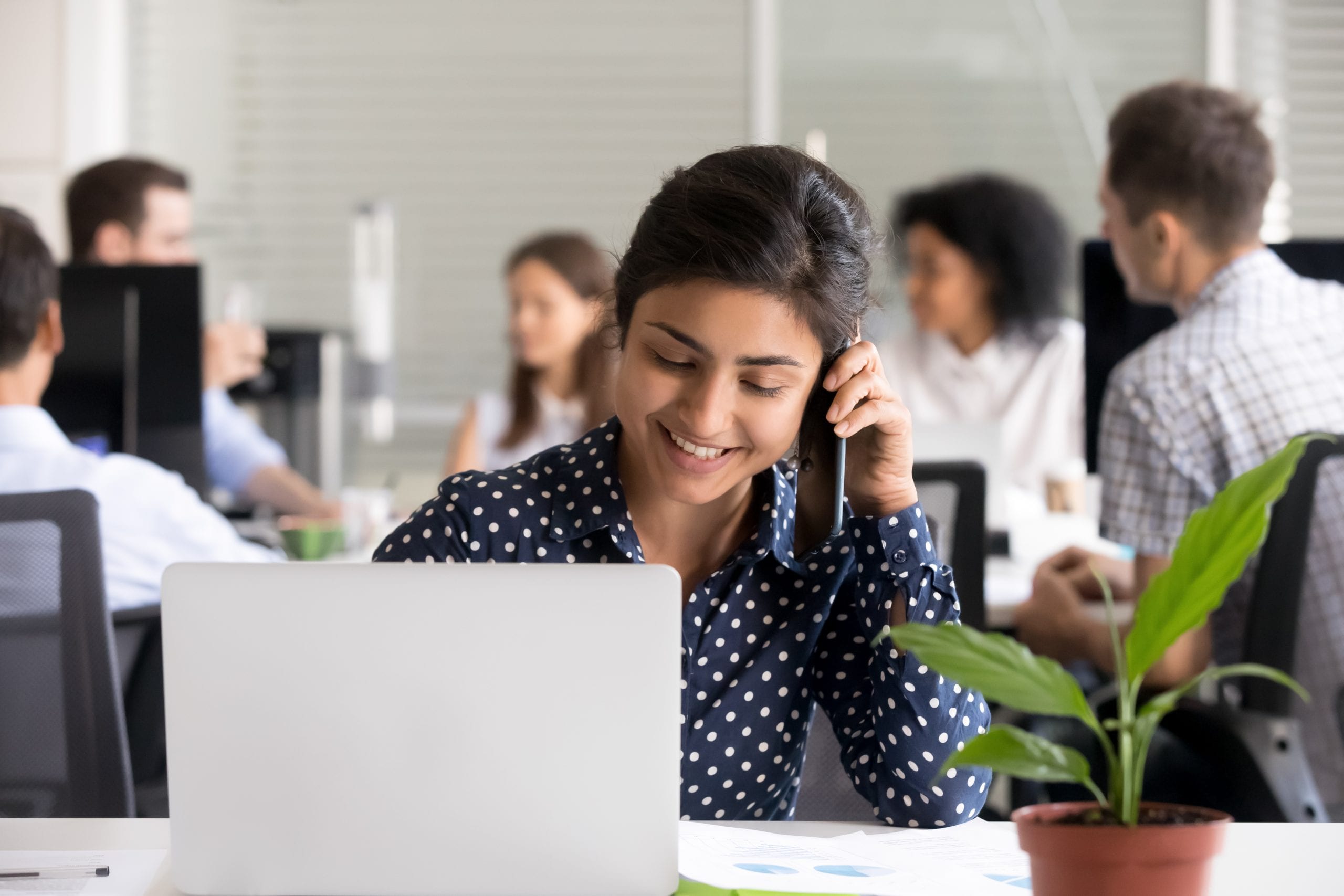 young woman in office setting talking on phone and smiling