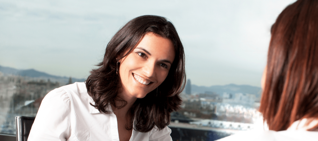 woman smiling broadly while talking to another woman during motivational interviewing