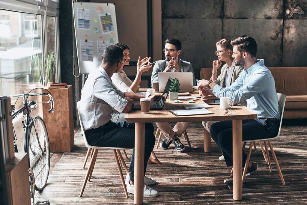 five people sitting around a table calmly discussing business options for software implementation