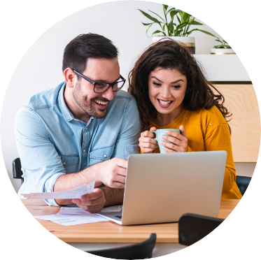 young couple looking at laptop while enjoying coffee at their kitchen table