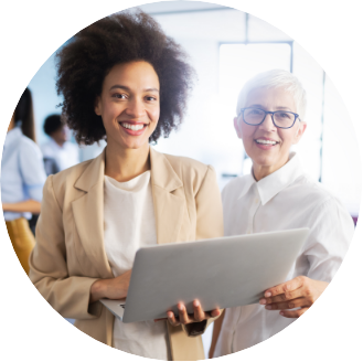 two female clinical directors holding a laptop while smiling into camera