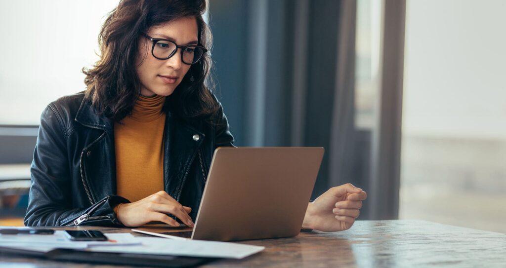 serious looking woman working at a laptop in a conference room