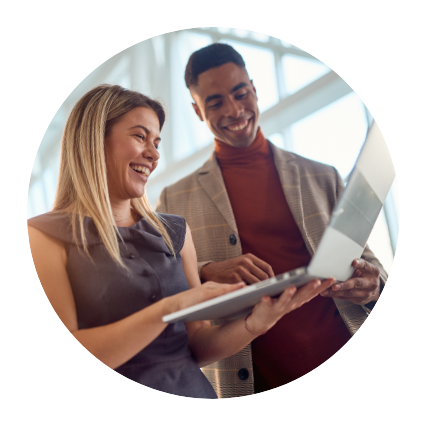 male and female business professionals study a laptop together while smiling