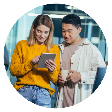 young woman interacting with tablet while young man looks on and sips coffee