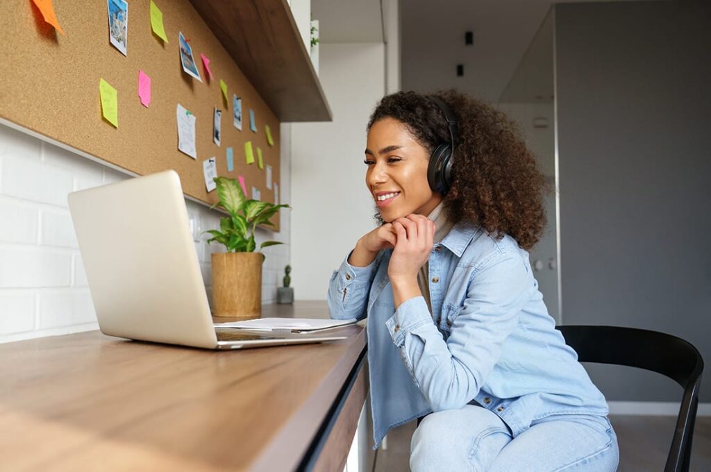 woman staring into laptop and smiling while engaged in telehealth session