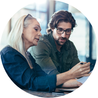 older woman and younger man looking at documents and discussing business development needs