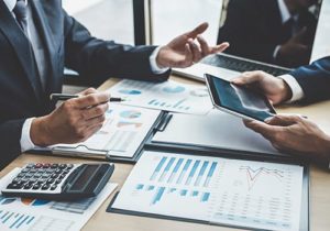 close up of two individuals with chart, papers, and calculators discussing finance