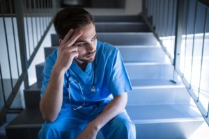 man sitting on stairs looking thoughtful as he considers common behavioral health compliance issues