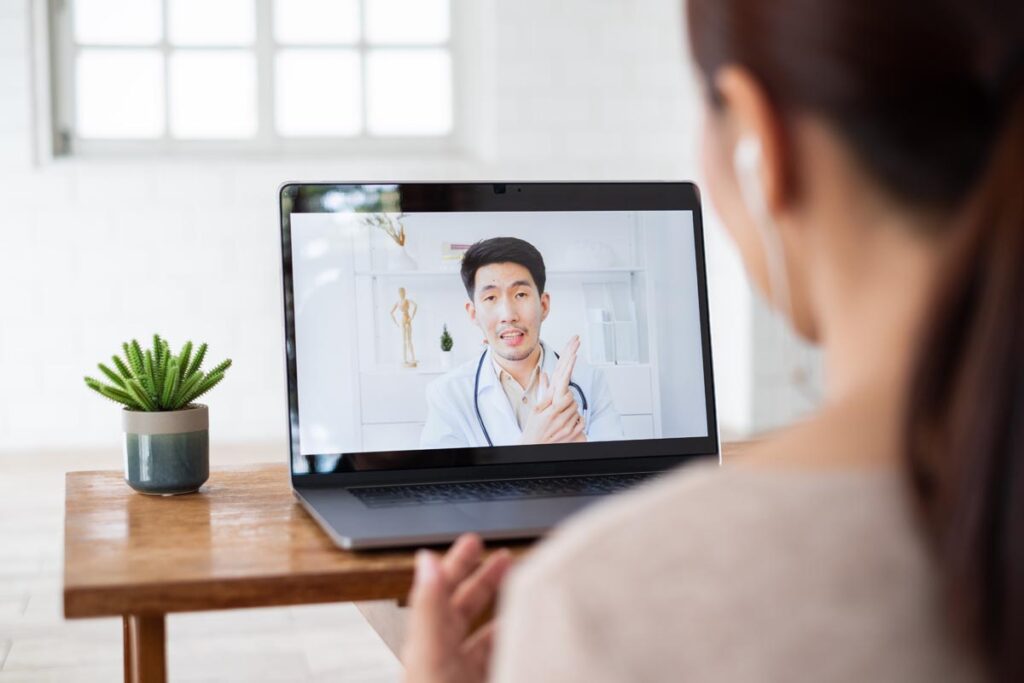 a person watches a doctor talking about hipaa and telehealth on a computer