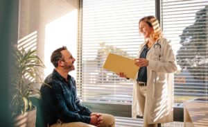 a doctor holds a folder and discusses alumni management benefits with another person