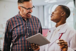 a doctor holds an ipad talking with someone about how to improve patient outcomes