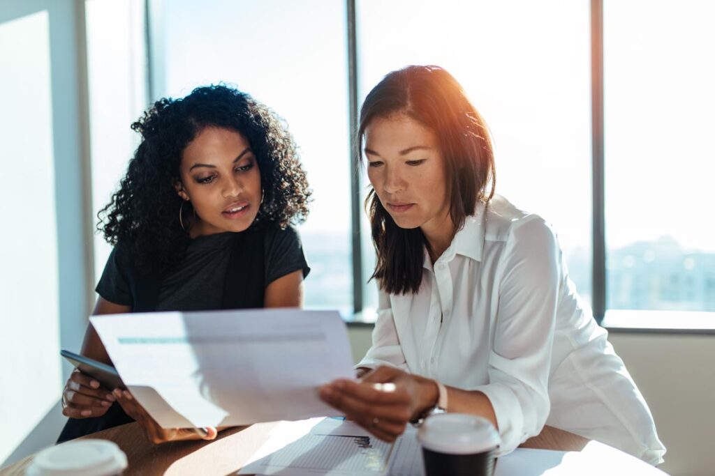 a person sharing finances with investors holds up a report for another to review