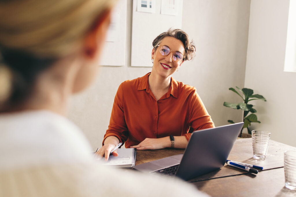 an accountant sits at a laptop explaining the benefits of behavioral health financial management to someone