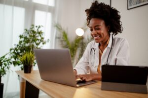 Smiling healthcare professional using a laptop at her desk.